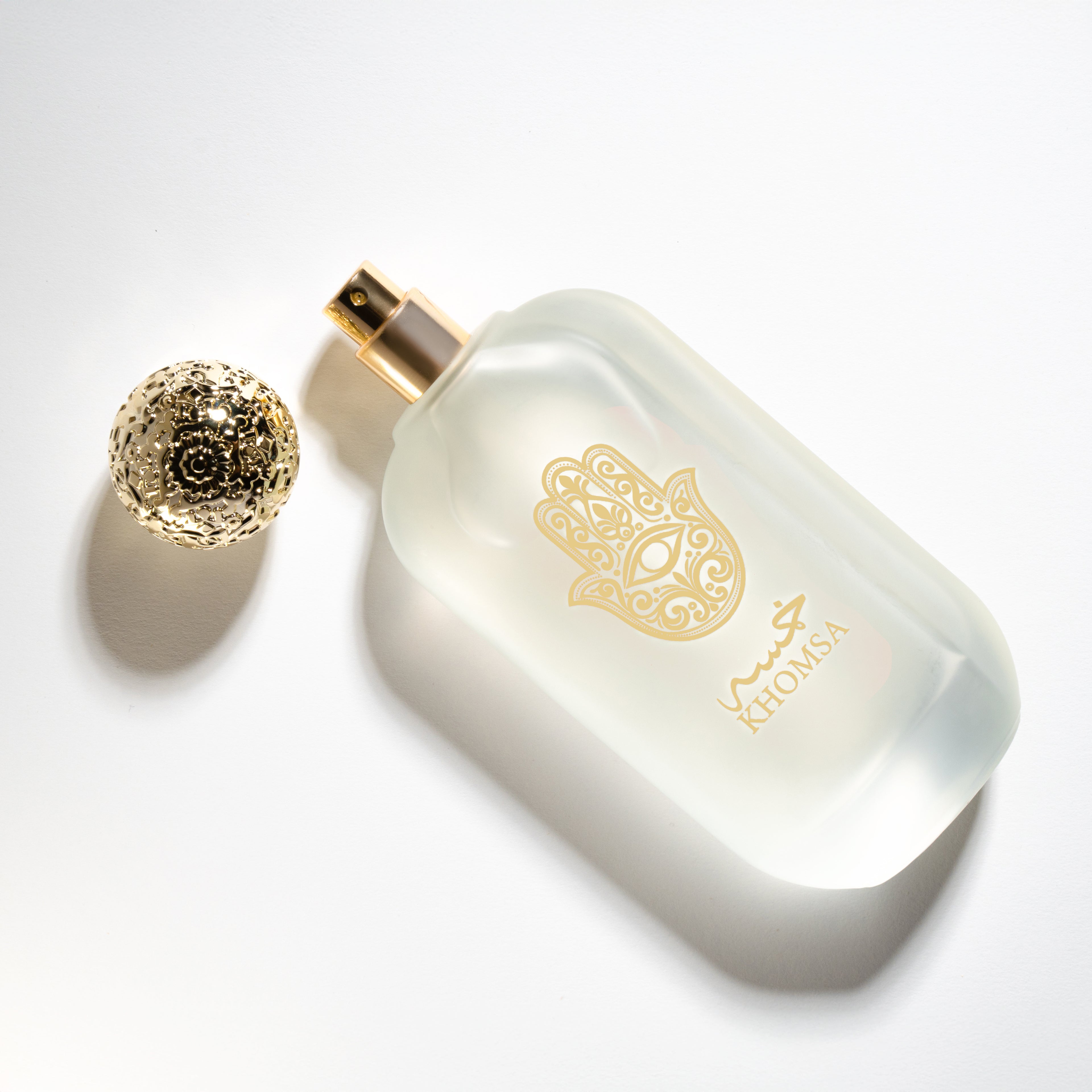 Perfume bottle with gold cap and decorative logo on a white background